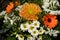 A close-up picture of a bouquet of funeral flowers. White, yellow and orange flowers with green leaves