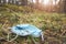 Close up picture of a discarded disposable medical face mask in the forest, selective focus