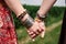 Close-up picture of hands with colorful bracelets and various rings, holding each other. Hippie women, wearing boho style clothes