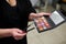 Close-up picture of make-up tools in female hands in beauty salon. Professional eye shadow palette in red shades and brushes for