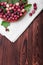 Close-up picture of ripe bright red gooseberries in a basket on a gray bag and wooden table.