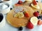 Close-up picture of a sweet breakfast composed of pancakes, fresh berries and fruits, ricotta cheese, jam and honey.