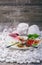 A close-up picture of a white plate full of delicious food and a wineglass on a wooden background. Tasty delicatessen on