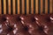 Close-up of a piece of artificial brown leather on a wooden background, upholstered furniture in retro Chesterfield