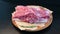 Close-up. A piece of raw fresh meat rotates on a plate on a dark background