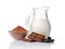 Close-up pieces of chocolate bar with cocoa beans, bowl of cocoa powder and glass jug of milk