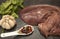 Close up of pieces of fresh raw beef liver, onion, garlic, spices, salt on the stone plate on a white background