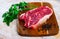 Close up of pieces of striploin served with parley on wooden table