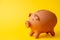 Close-up piggy bank made of clay, yellow background, horizontal