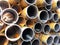 Close-up of a pile of rusty metal pipes laying on the street