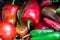 Close up of a pile of sweet and hot peppers, mostly red and green.