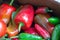 Close up of a pile of sweet and hot peppers, mostly red and green.