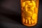 Close-up of pills or medication tablets in an orange pill bottle standing on a black table