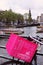 Close up of a pink bicycle basket with tour boats behind