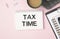 Close up pink notepad with word TAX TIME putting