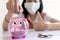 Close up of pink piggy bank,Concept of frugal,thrifty and economical, good saver, asian child girl put coin into piggy bank,saving
