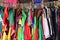 Close-up of pink, red yellow orange, purple, pink, and many designs men and women modern dresses hanging on wood rod in market for