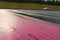 A close up of a pink sports car breezing around a wide corner on a wet tarmac raceway. Speed drive concept. AI