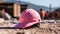 Close up of a pink Working Helmet on Gravel. Blurred Construction Site Background