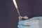 Close-up of a pipette pouring liquid into a small disposable test tube on a dark background