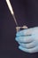 Close-up of a pipette pouring liquid into a small disposable test tube on a dark background