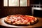 Close up on a pizza on a wooden table in front of a stove and a window.