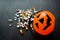 Close up plastic Pumpkin basket with colorful blurred pills poured out from it. Coronavirus Halloween concept. Copy space, black