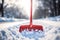 Close-up of a plastic snow shovel while clearing a sidewalk