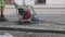 Close-up of plate compactor. Building worker leading the plate compactor