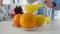 Close-up of plate with healthful vitamin fruits and blurred senior man pouring juice at background. Oranges and lemons