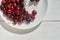 Close-up of a plate of ripe cherries in a white plate on a white wooden background. With space to copy. Top view of a