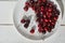 Close-up of a plate of ripe cherries in a white plate on a white wooden background. With space to copy. Top view of a