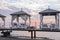 Close-up platform with row of gazebos with sunbeds at dawn.