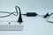 Close up plug in Adapter power cord charger with blurred laptop computer on white