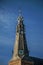 Close-up of pointed steeple roof in a church made of bricks, golden clock and blue sky on sunset at Weesp.