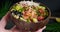 Close-up poke bowl video, person holding a bowl with salmon, vegetables and rice served in bowl, poke dish, 4k video