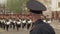 Close-up of a police officer watching soldiers marching in a military parade.