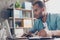 Close up of ponder young african handsome man. He is wearing casual smart, sitting at the workplace, looking in the laptop screen,