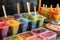 close-up of popsicle stand, with colorful frozen treats and spoons in view