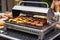 close-up of a portable grill with sizzling hot dogs and hamburgers