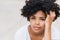 Close-up portait of beautiful young black woman with sad, pensive, reflective look, against white wall background with copy space