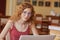 Close up portait of teenage girl sitting at table in front of opened lap top, wearing casual maroon t shirt, student in eyewear