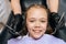 Close-up portrait of adorable little girl smiling looking at camera sitting in stomatology seat while pediatric dentist