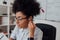 Close up portrait of afro american woman, female teacher adjusting wireless headphones while giving online class through