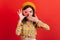 Close-up portrait of amazed green-eyed girl holding tasty donut. Lady in beret and shirt covers her mouth.