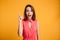 Close-up portrait of amazed pretty young woman in red dress pointing with finger, looking at camera with open mouth