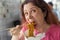 Close-up portrait of an amusing crazy young pretty girl eating chinese noodles with wooden chopsticks sitting in a cafe