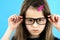 Close up portrait of angry displeased child school girl wearing looking glasses isolated on blue background