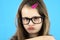 Close up portrait of angry displeased child school girl wearing looking glasses isolated on blue background