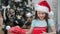 Close-up portrait of astonished girl in Santa Claus cap opening gift box having positive emotion